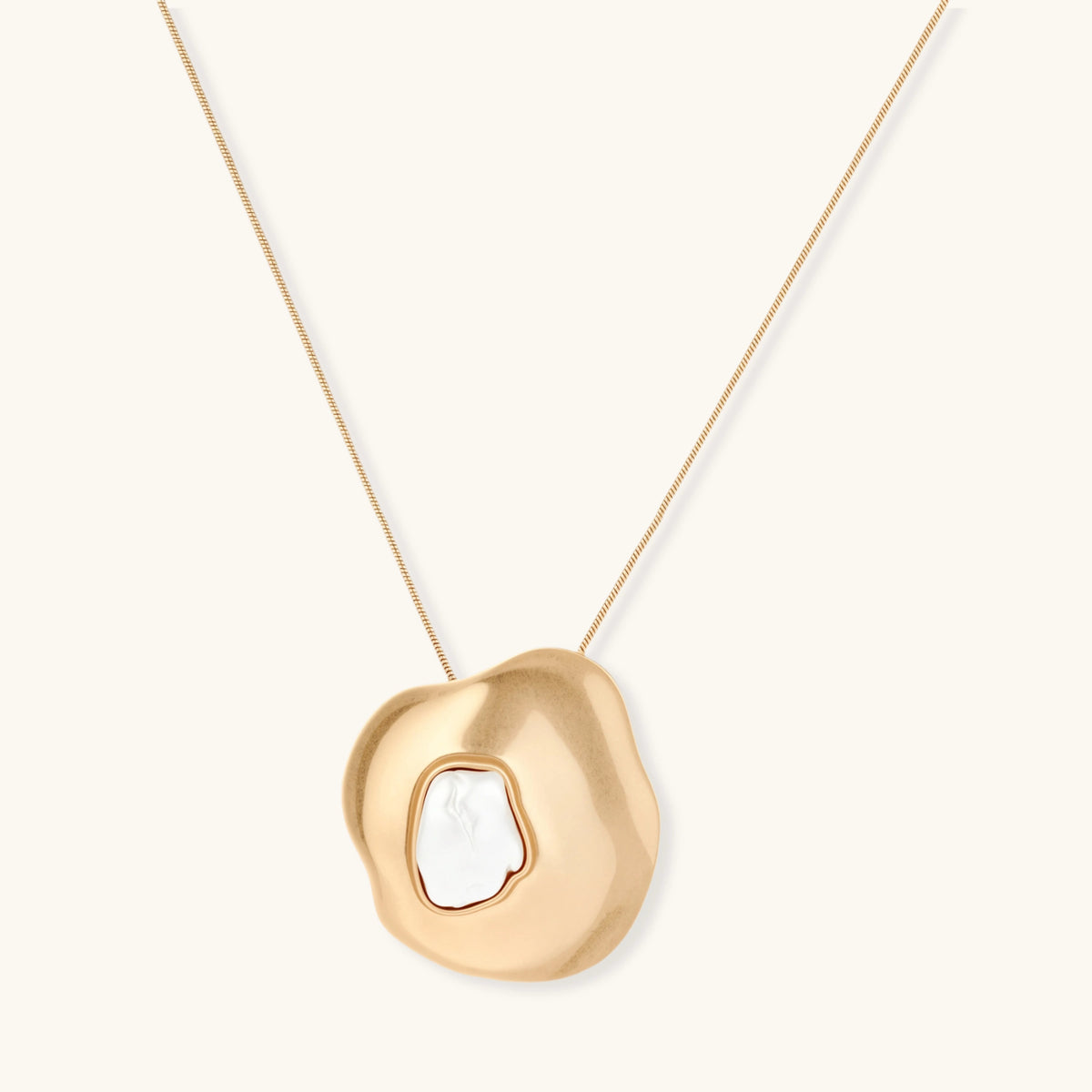 Organic-shaped gold pendant necklace with baroque pearl accent on adjustable chain, displayed against neutral background.