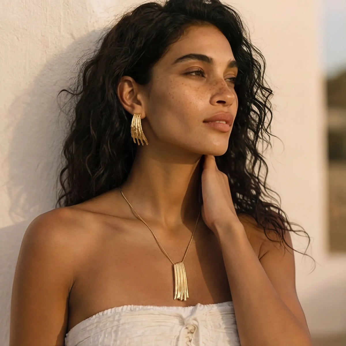 Woman wearing a matching gold necklace and earrings from Tessheart Jewelry