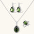 White gold plated jewelry set with green teardrop gemstones and cubic zirconia halos on cream background.