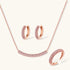 Rose gold pavé zirconia bar necklace, hoop earrings, and open ring set with pink stones on cream background.
