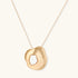 Organic-shaped gold pendant necklace with baroque pearl accent on adjustable chain, displayed against neutral background.
