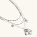 Multi-strand layered necklace set with silver chains, white pearls, star charm, heart pendant, and ornate decorative piece