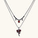 Dark layered necklace set with black chains and red heart pendants, featuring gothic snake design on white background