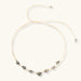 Adjustable cream cord necklace with white spotted stone beads featuring black speckles on neutral background