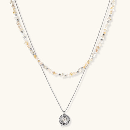 Two-layer necklace with natural stone chips and eco-brass beads, featuring a circular wrapped pendant on cream background.