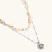 Two-layer necklace with natural stone chips and eco-brass beads, featuring a circular wrapped pendant on cream background.