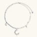 Silver-toned crescent moon pendant with star accents on pearl and chain necklace against white background.