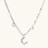 Silver-toned crescent moon pendant with star accents on pearl and chain necklace against white background.