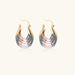 Gold hoop earrings with gradient blue-to-pink enamel in ribbed fan design on beige background