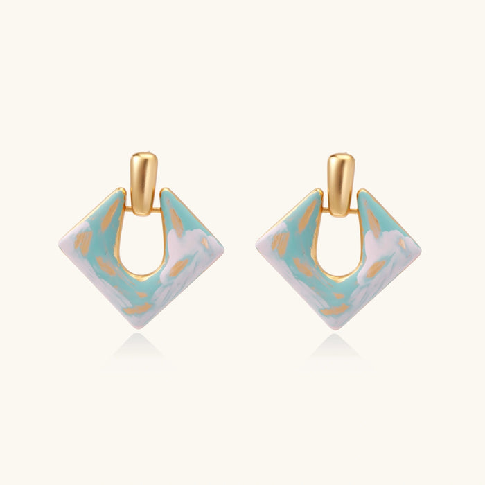 Geometric square enamel earrings with marbled turquoise and lavender pattern, gold U-shaped connector on cream background.