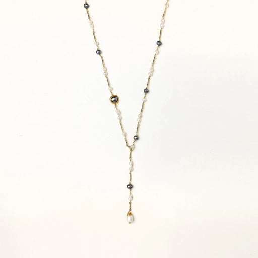 Y-shaped gold-plated necklace with white and gray freshwater pearls on cream background, showing adjustable drop design.