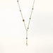 Y-shaped gold-plated necklace with white and gray freshwater pearls on cream background, showing adjustable drop design.