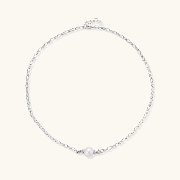 Dainty rhodium-plated silver chain necklace with centered 10mm freshwater pearl and crystal accents on cream background