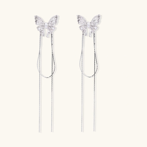 Pair of silver threader earrings with crystal butterfly tops and long chain drops on cream background.