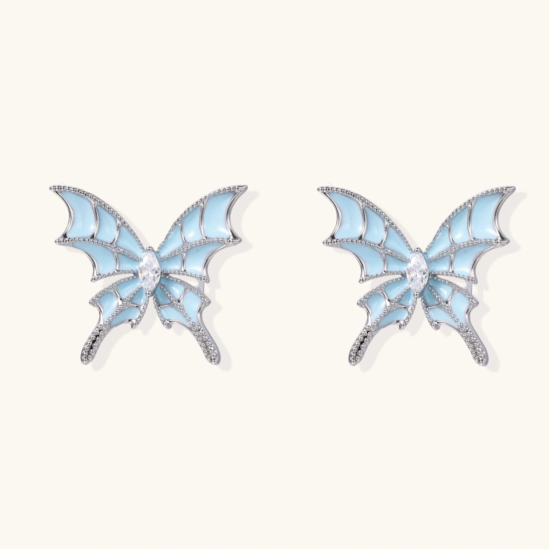Long silver-tone earrings with powder blue enamel butterfly studs and flowing chain tassels on cream background
