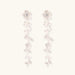 Long sterling silver drop earrings with delicate floral vine design and crystal accents on white background