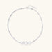 Sterling silver multi-strand necklace with three brushed round beads on cream background
