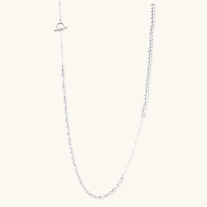 Long sterling silver beaded necklace with graduated sphere design, toggle clasp, and delicate chain extension on white background