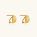 Pair of brushed gold dome earrings with clip backs showing textured matte finish on cream background