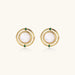 Circular gold stud earrings with iridescent mother-of-pearl center and green zirconia accents on cream background.