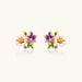 Cluster-style stud earrings with purple pansies, white daisies, yellow centers, and green leaves in glossy enamel finish