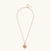 Heart-shaped pendant with pink enamel, rose design, freshwater pearl flower, and gold scalloped frame on delicate chain