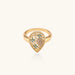 Teardrop-shaped gold-plated ring with turquoise enamel flowers and crystal pavé detail on cream background