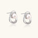 White gold-plated brass earrings with circular design, freshwater pearl center, and diamond accents