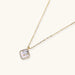 Gold quatrefoil pendant with crystal center on iridescent mother-of-pearl base, adjustable gold chain on cream background