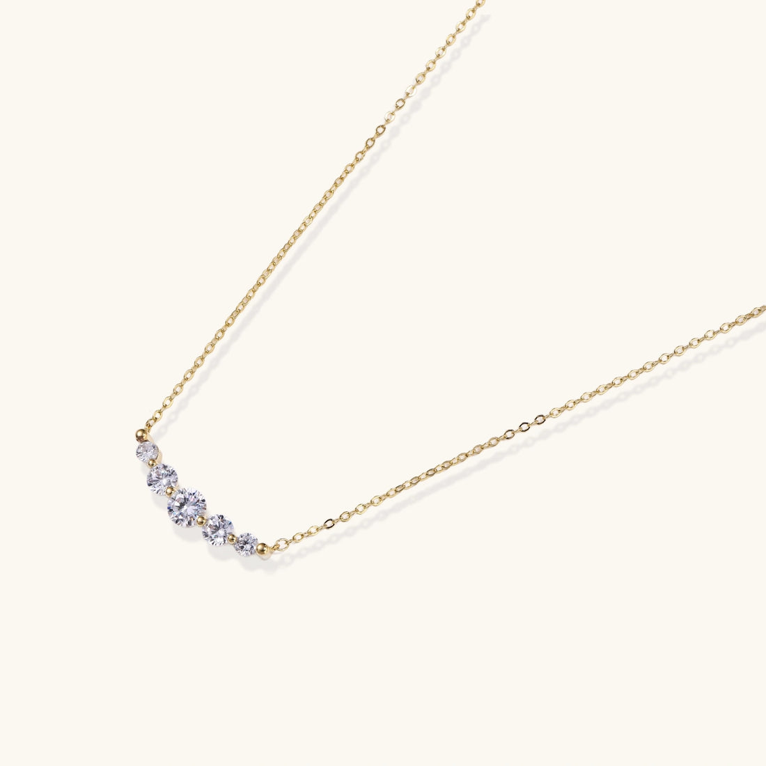 Delicate 14K gold-plated necklace with five graduated zirconia stones arranged in a curved arc on fine chain