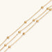 Three-strand gold-plated bracelet with clustered ball beads and adjustable clasp on cream background