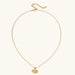Layered necklace with green stone beads, gold spacers, white accents, and protective eye pendant on cream background.