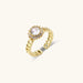 Gold-plated adjustable ring with twisted chain band, central cubic zirconia stone surrounded by crystal halo on cream background