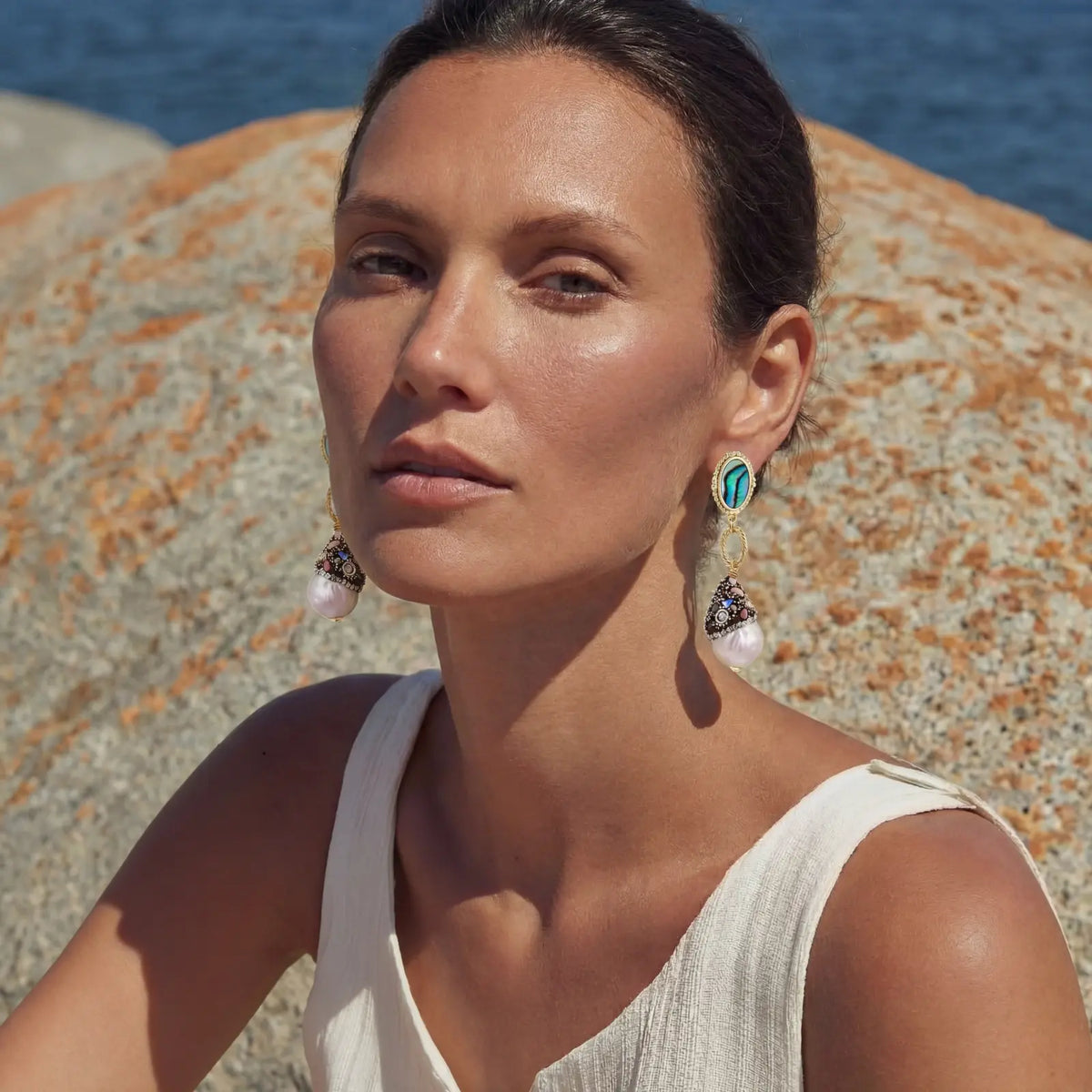 Woman wearing elegant baroque pearl and abalone drop earrings