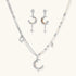 Mixed-metal jewelry set featuring layered necklaces with crescent moon pendant and pearl beads, plus matching star-drop earrings.