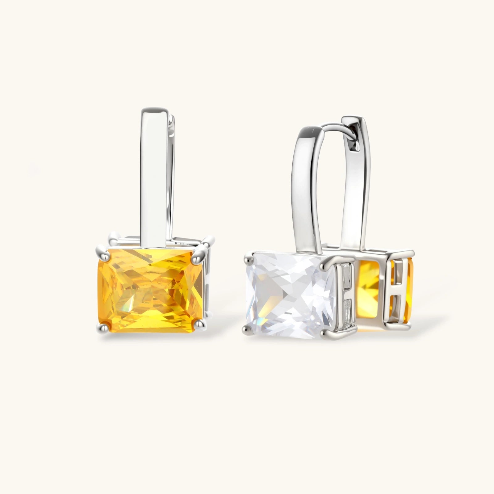 Silver curb-chain necklace and hoop drop earrings set with paired yellow and clear square zirconia stones.