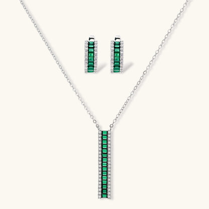 White gold plated jewelry set with emerald green rectangular stones and clear crystals in geometric rows on white background.