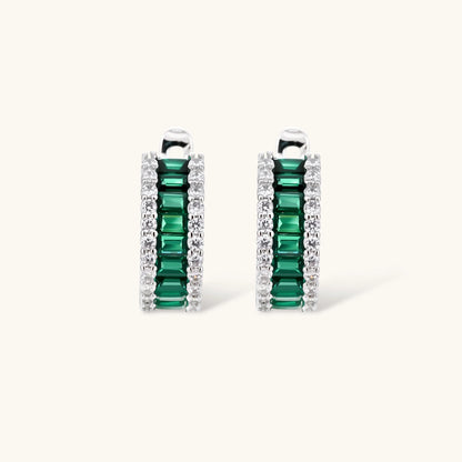 White gold plated jewelry set with emerald green rectangular stones and clear crystals in geometric rows on white background.